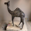 A detailed close-up highlighting the intricate etched metallic patterns and traditional craftsmanship of the decorative camel statue.