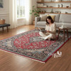 A luxurious 150x100 silk machinemade Persian rug featuring a rich red center medallion, intricate floral patterns, and elegant fringe details in a modern living room setting.