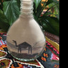 Studio view of the custom Mohamed Salah sand portrait bottle showcasing fine artisan craftsmanship against a green foliage background.