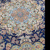 Detailed top-down view of the silver and ivory floral vines against the deep navy blue field of the large silk rug.