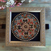 A stunning circular embossed pottery plate mounted securely inside a carved decorative frame for interior display.