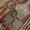 A premium metallic key ring featuring an intricate 3D pattern inspired by traditional UAE coins and currency.