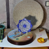 Styled tabletop view of the detailed white-ground and blue enameled Minakari decorative copper plate on a decorative stand with crafts.