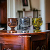 A stylish tabletop display of the bronze, silver, and gold miniature shot glass set resting on a wooden stand.