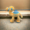 A charming plush camel stuffed animal showcasing vibrant blue and orange saddle decorations.