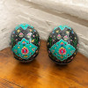 A professional product shot of the hand-painted ostrich egg art piece styled elegantly on a wooden display surface.