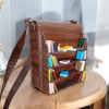 A handcrafted brown leather messenger bag featuring a unique 3D sculpted bookshelf design on the front flap