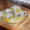 A beautiful hand-painted ceramic tea set complete with a teapot, cups, and a matching yellow serving tray