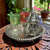 Traditional high-pour tea ceremony using a Moroccan silver teapot and tinted glasses on an engraved tray
