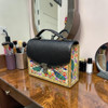 Front view of the premium embossed peacock genuine cow leather artisan handbag, showcasing the vibrant hand-painted floral and bird art under a rich burgundy top flap with its attached leather shoulder strap.