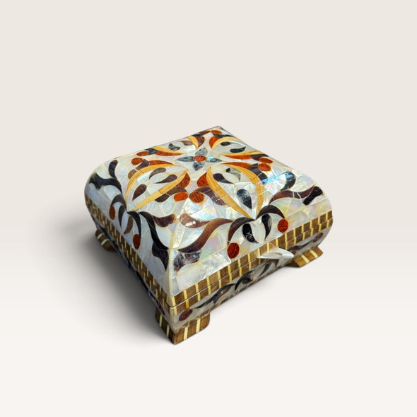 Open mother-of-pearl jewelry box holding rings, earrings and a necklace