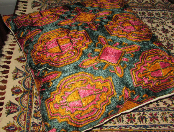 Extreme close-up of the textured hand-sewn needlework and vibrant thread colors on a Kashmiri pillow cover.