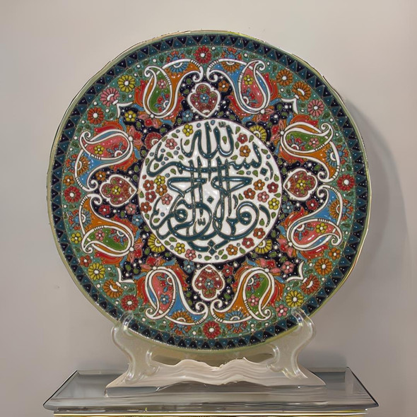 A premium 25 cm handmade clay plate featuring embossed Islamic calligraphy surrounded by a vibrant, multi-colored floral mosaic for wall decor.
