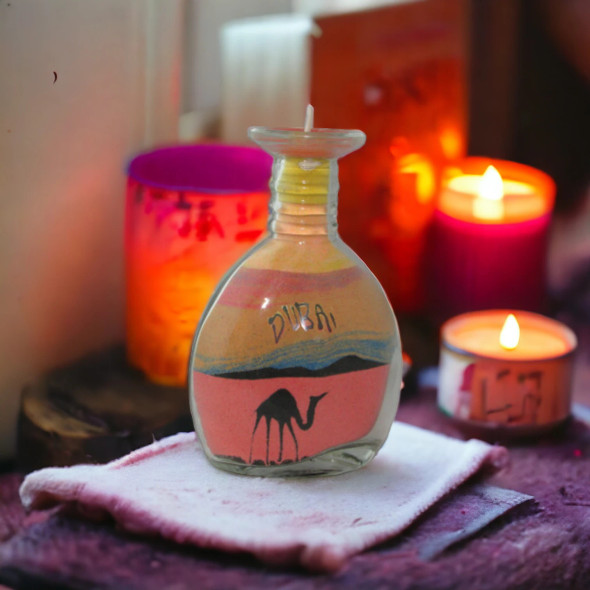 A large 13x8 cm flat glass bottle featuring hand-poured desert sand art with camels and palm trees.