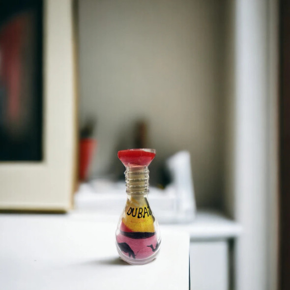A 10 cm medium round glass jar featuring handmade sand art of a Dubai desert landscape with multiple camels.