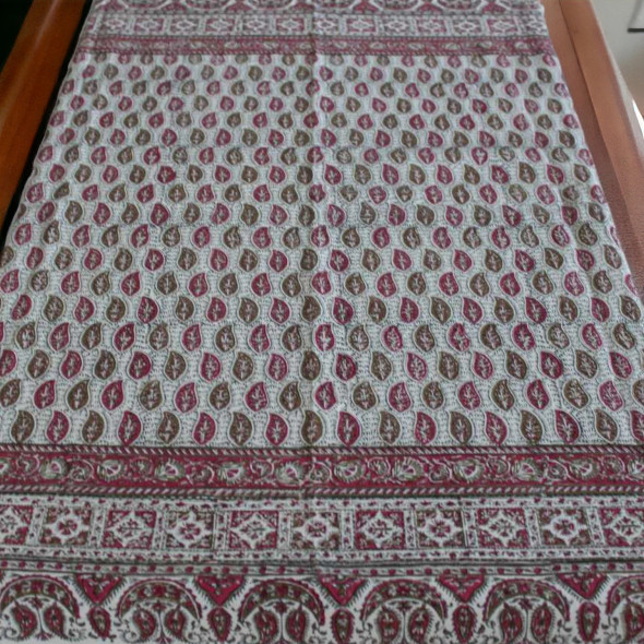 A bohemian-style dining room setup featuring a floral Persian tapestry as the central table decor.