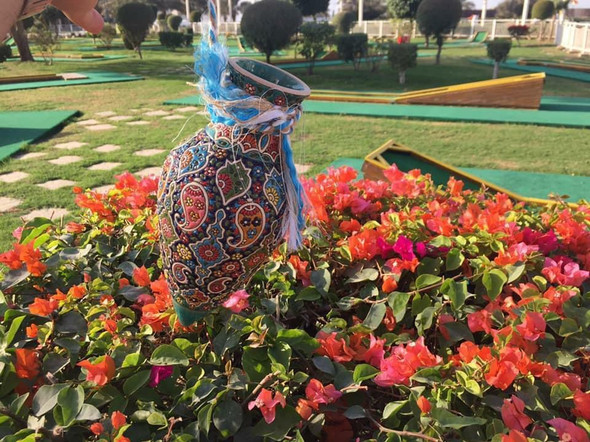 A teardrop-shaped Persian wall-hanging ceramic vase with turquoise and white enamel floral patterns