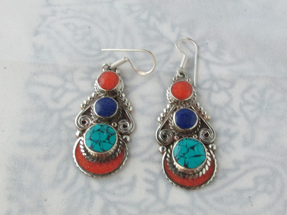 The pair of handcrafted earrings displayed together, emphasizing their balanced design and the vibrant contrast between the turquoise, lapis, and coral stones.