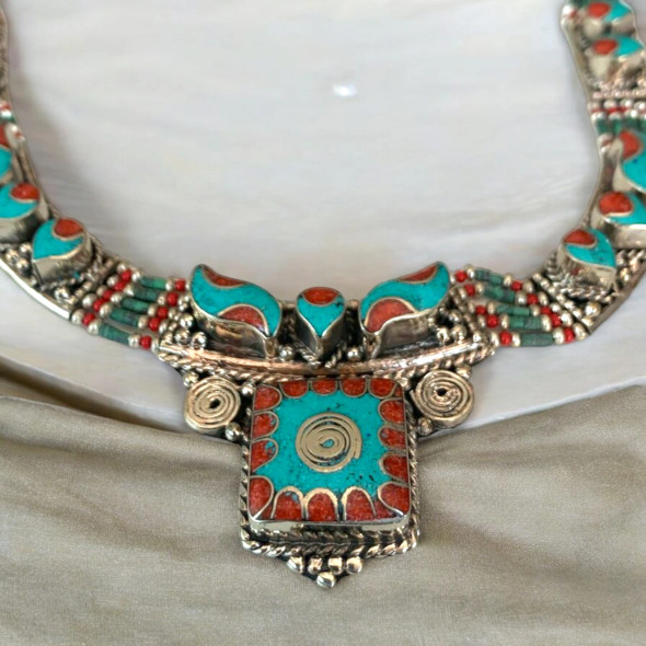 A stunning handcrafted necklace with turquoise, red coral, and green stone beads, perfect for adding a bohemian touch to any outfit.