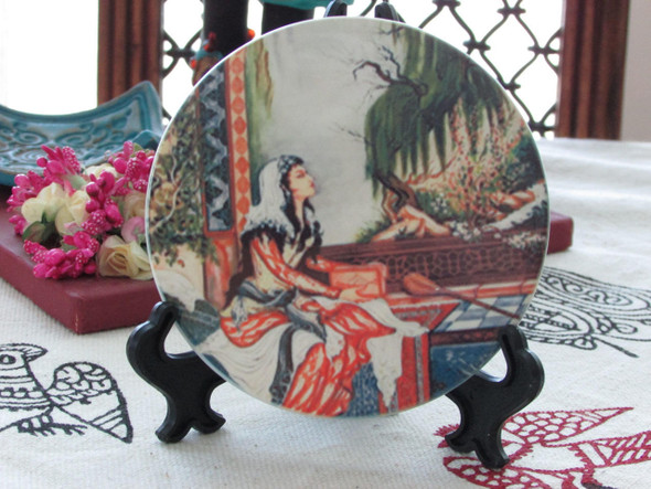 The round ceramic coaster showcased on a black display stand, emphasizing its artistic illustration and high-quality finish.