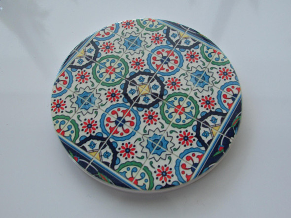 A sophisticated round ceramic coaster that blends functional design with a rich, traditional artistic motif.