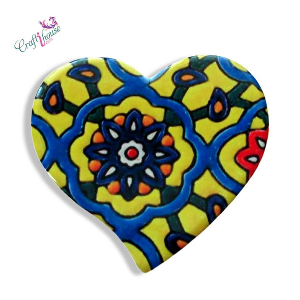 A heart-shaped printed ceramic fridge magnet featuring a vibrant yellow, blue, orange, and red geometric mosaic tile pattern with a central floral medallion.