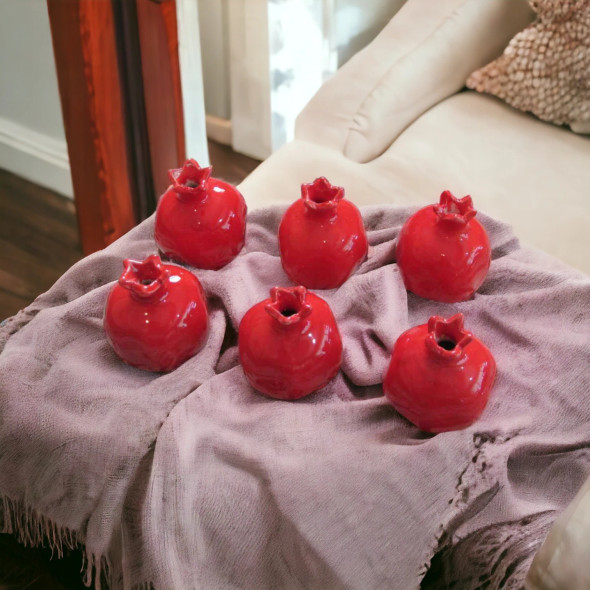 A vibrant, glossy red glazed ceramic pomegranate handmade from clay, perfect as a symbolic home decor piece.