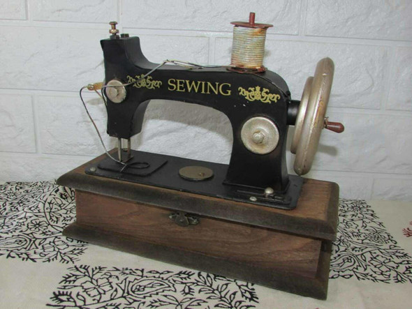 Close-up of the metal hand wheel and needle mechanism on the decorative vintage sewing machine sculpture.