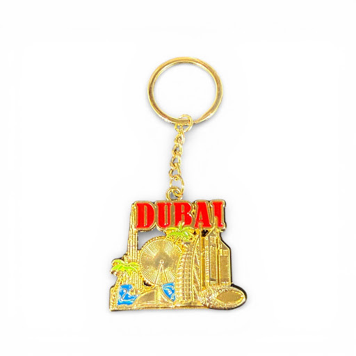 A premium gold-toned keychain featuring the Dubai skyline with red "DUBAI" text and blue enamel accents.