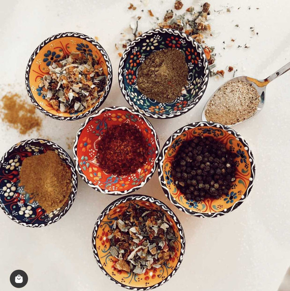 A collection of small, colorful hand-painted Turkish ceramic bowls with assorted floral patterns on a rustic background.