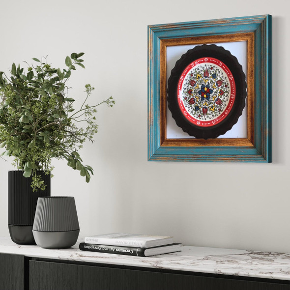 Close-up of the delicate hand-painted motifs and the brilliant glossy glaze of the ceramic plate within its professional gallery frame.