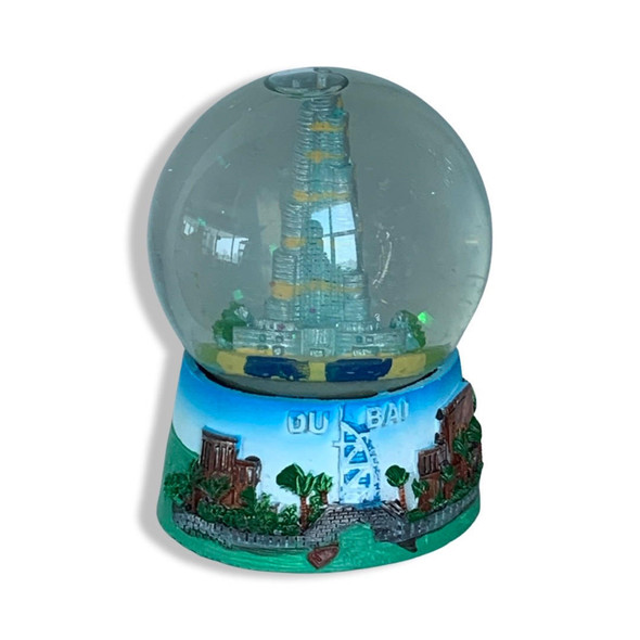 Close-up view of the detailed city architecture inside the water globe and the painted scenery on the pedestal.