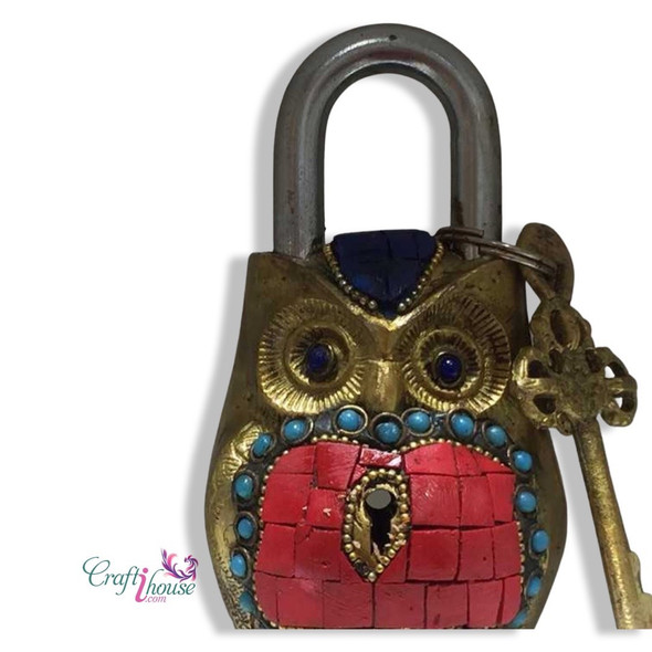 Close-up of the turquoise and red stone-style inlays and the keyhole on the decorative brass owl lock.