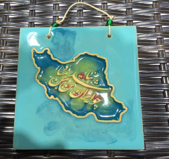 A detailed close-up highlighting the intricate golden lettering and glossy glazed ceramic surface of the map-shaped motif.