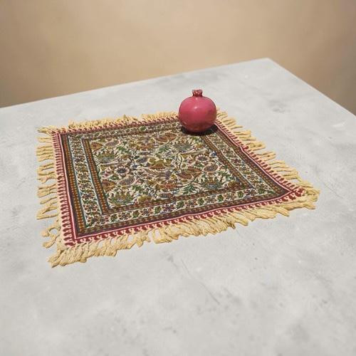 A 40x40 cm washable handmade Ghalamkari cotton place mat featuring intricate block-printed patterns and white fringe.