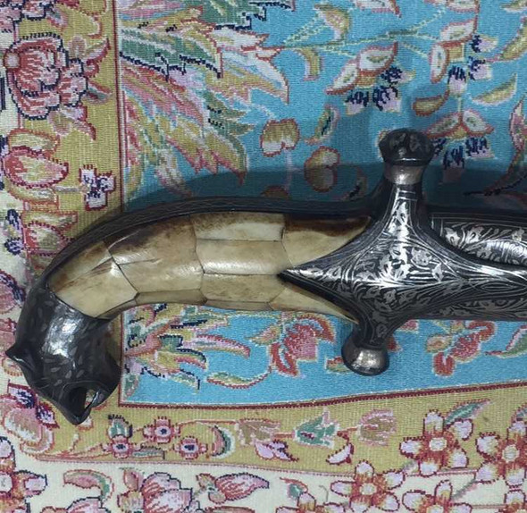 Close-up of the intricate hand-carved tiger head hilt made from polished white camel bone.