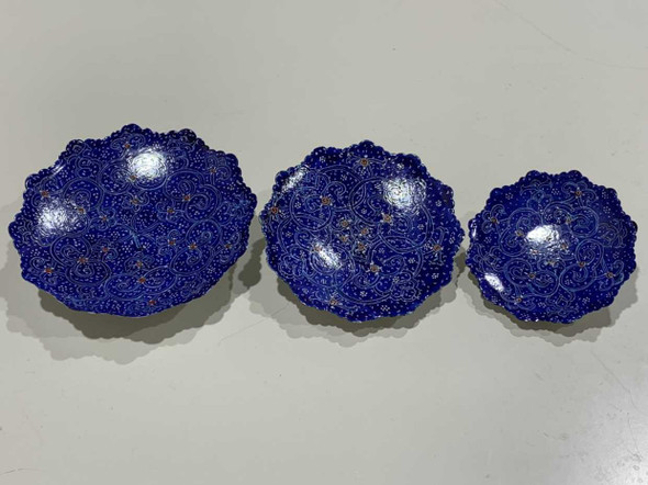 Detailed view of the intricate blue floral enamel patterns on the set of three copper plates.