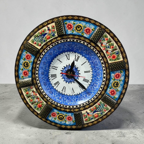 A 33 cm handmade wooden wall clock featuring a central blue Minakari copper plate with a hand-painted peacock and floral design.