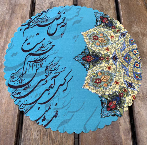 A 28 cm round turquoise velvet placemat on a wooden surface featuring Persian calligraphy and gold floral illumination art.