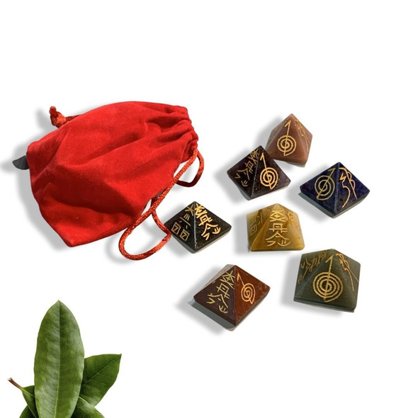A professional product shot of the crystal pyramids and red storage pouch arranged neatly on a clean studio backdrop.