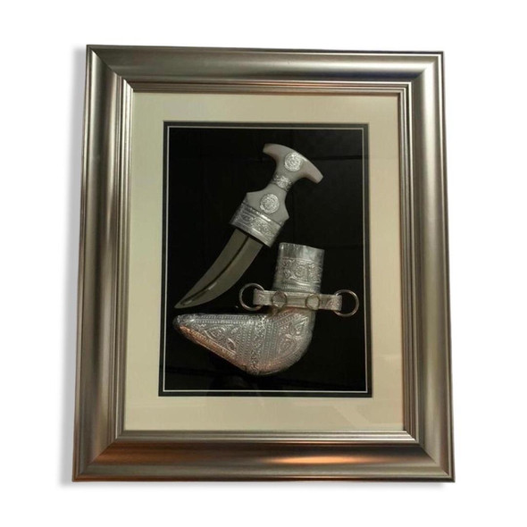 Detailed close-up of the framed cultural souvenir, highlighting the intricate geometric reliefs and traditional medallion engravings on the silver-tone dagger hilt and matching sheath.