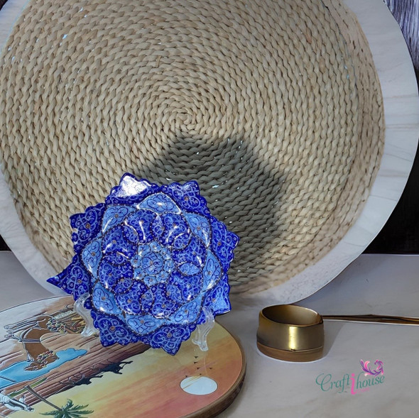 A professional product display shot of the 16 cm cobalt blue Minakari copper plate positioned against a woven background.