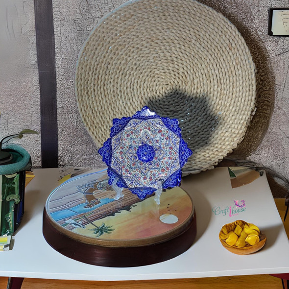 Styled tabletop view of the detailed white-ground and blue enameled Minakari decorative copper plate on a decorative stand with crafts.