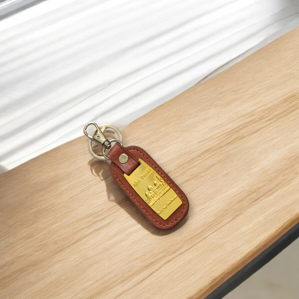 A stylish tabletop display of the genuine brown leather keychain resting on a wooden surface indoors.