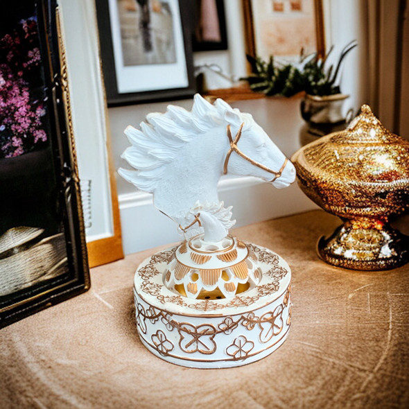 A stylish tabletop display of the horse head oud burner and its pierced cover resting on a textured fabric surface.