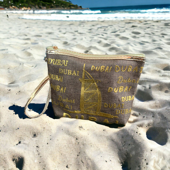 A stylish cosmetic and travel pouch adorned with a luxurious gold Dubai script design outdoors.