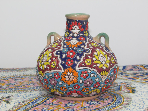 The 10 cm hand-enamel painted earthenware vase shown as a sophisticated decorative accent on a modern luxury bookshelf.