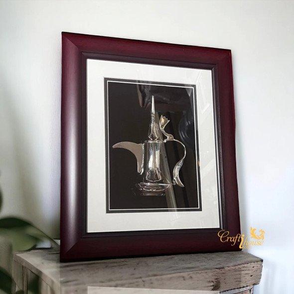 A professional product presentation of the decorative silver Dallah framed art piece from a premier UAE gift shop.