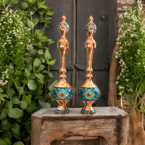 Detailed close-up of the vibrant, hand-painted floral enamel work on the base of these artisan-crafted copper pitchers.