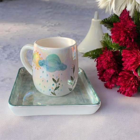 A professional product shot of the artistic ceramic mug and matching square saucer displayed outdoors in natural sunlight.